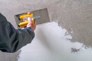 Construction worker - plastering and smoothing concrete wall wit