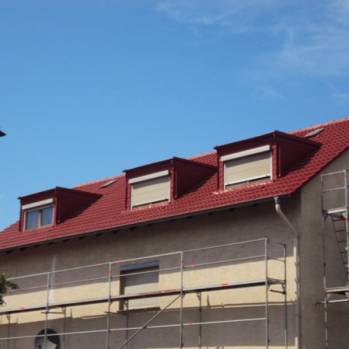 Sanierung eines Mehrfamilienhaus-Daches mit Beschichtung in Klassischrot